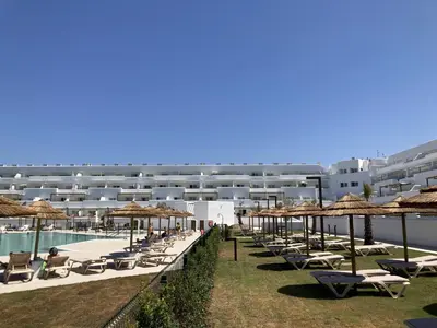 a row of chairs and umbrellas next to a swimming pool at Punta Candor Suites in Rota