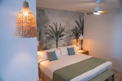 a bedroom with a bed with a painting on the wall at Punta Candor Suites in Rota