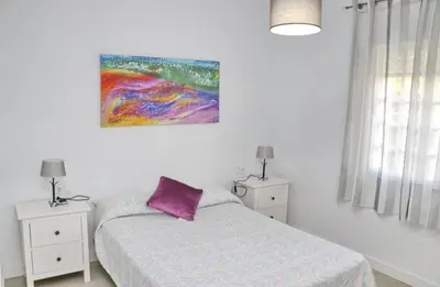 a bedroom with a bed and a painting on the wall at Chalet Cocle in Novo Sancti Petri