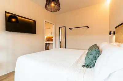 a bedroom with a white bed and a flat screen tv at Villa de Paradas in Cádiz