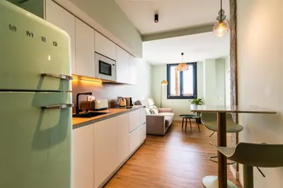 a kitchen with white cabinets and a living room at Villa de Paradas in Cádiz