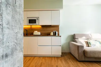 a kitchen with white cabinets and a couch at Villa de Paradas in Cádiz