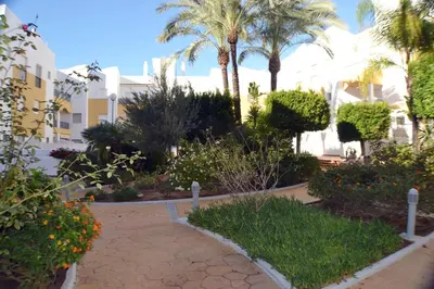 a garden with palm trees and flowers in front of a building at Costa Ballena - El Paraíso in Rota