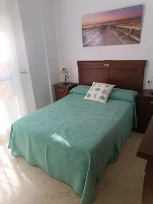 a bed with a green blanket and a pillow on it at Costa Ballena - El Paraíso in Rota