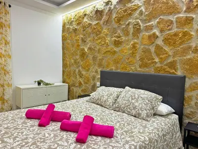 two pink pillows on a bed with a stone wall at Apartamento Acebuche - Ole Solutions in Jerez de la Frontera