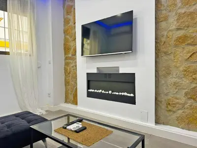 a living room with a fireplace and a tv on a wall at Apartamento Acebuche - Ole Solutions in Jerez de la Frontera