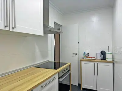 a small kitchen with white cabinets and a stove at Apartamento Acebuche - Ole Solutions in Jerez de la Frontera