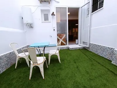 a patio with green grass and a table and chairs at LA CASA DE LAS BICIS in Cádiz