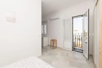 a white room with a large window and a bed at Verano en Chiclana in Chiclana de la Frontera