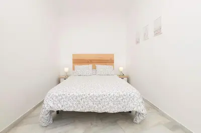 a white bedroom with a bed and two candles at Verano en Chiclana in Chiclana de la Frontera