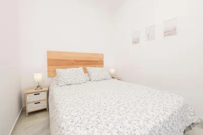 a bedroom with a white bed with a wooden headboard at Verano en Chiclana in Chiclana de la Frontera