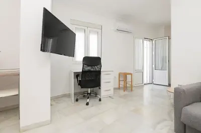 a room with a chair and a desk with a television at Verano en Chiclana in Chiclana de la Frontera