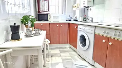a kitchen with a table and a washing machine at RESIDENCIAL VICTORIA CENTRO in Sanlúcar de Barrameda