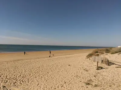 a beach with people walking on the sand and the ocean at Piscina y garaje a 300 m de playa OJO VER CORREO NO DESEADO SI NO LLEGA RESPUESTA in Rota
