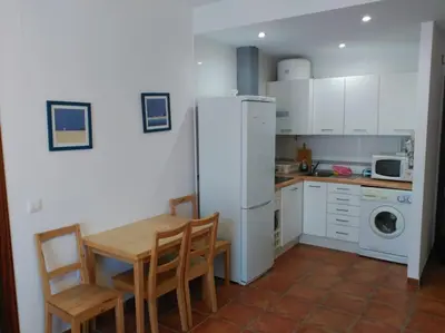a kitchen with a table and a white refrigerator at Piscina y garaje a 300 m de playa OJO VER CORREO NO DESEADO SI NO LLEGA RESPUESTA in Rota