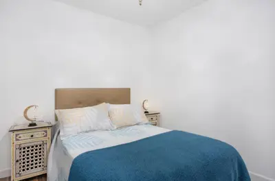 a bed with a blue blanket and two night stands at APARTAMENTO BRIANNA in Jerez de la Frontera