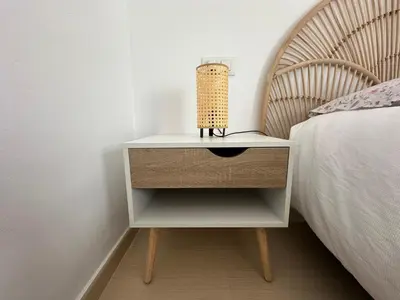 a bedside table with a lamp on it next to a bed at Apartamento Jardín de Cano - Preferente familias y mayores de 25 años in El Puerto de Santa María