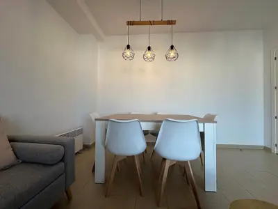 a dining room with a table and two white chairs at Apartamento Jardín de Cano - Preferente familias y mayores de 25 años in El Puerto de Santa María