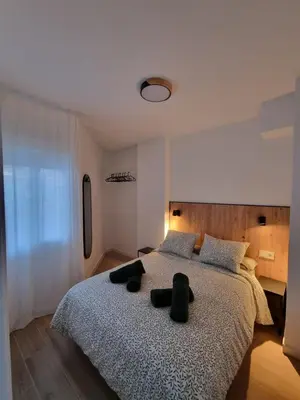 a bedroom with a large bed with two black pillows at Apartamento Playa Victoria I in Cádiz