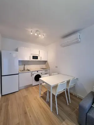 a kitchen and dining room with a white table and chairs at Apartamento Playa Victoria I in Cádiz