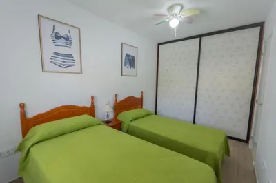 two beds in a room with green sheets at Chiclana.Balconera.1ªlínea playa in Chiclana de la Frontera