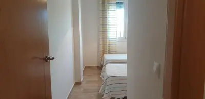 two beds in a room with a table with a lamp at Chiclana Costa in Chiclana de la Frontera