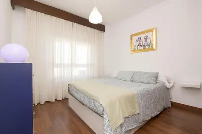 a white bedroom with a bed and a window at El Trebol in El Puerto de Santa María