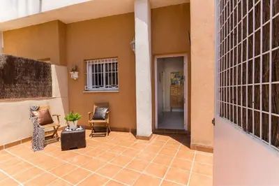 a porch of a house with chairs and a door at Apartamento planta baja con piscina privada a 50 m de la playa in Sanlúcar de Barrameda