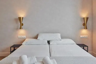 two beds in a room with two lamps on the wall at VG - Villa de Andas suites in Cádiz