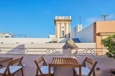 a table and chairs on a balcony with a lighthouse at VG - Villa de Andas suites in Cádiz