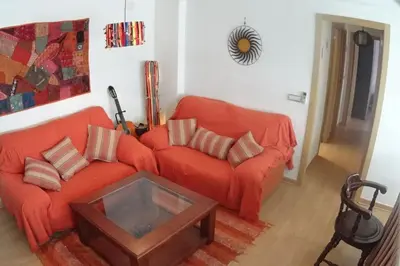 a living room with an orange couch and a table at Apartamento cerca del centro in Jerez de la Frontera