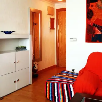 a bedroom with a red bed and a white cabinet at Apartamento cerca del centro in Jerez de la Frontera
