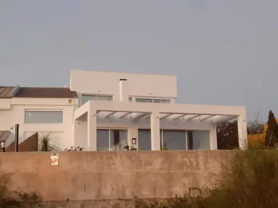 a large white house behind a concrete fence at Santa Catalina primera línea de mar con vistas a Cádiz in El Puerto de Santa María