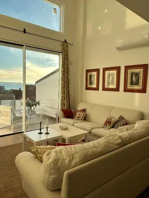 a living room with two couches and a large window at Santa Catalina primera línea de mar con vistas a Cádiz in El Puerto de Santa María