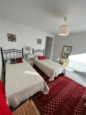 a bedroom with two beds and a red rug at Santa Catalina primera línea de mar con vistas a Cádiz in El Puerto de Santa María