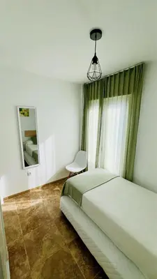 a white bedroom with a bed and two windows at Altos de Jerez & Parking Privado in Jerez de la Frontera