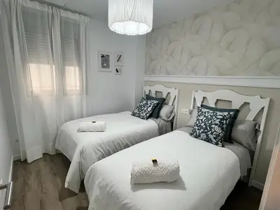 a bedroom with two beds and a chandelier at Jardines del Porvenir 4 in Puerto Real