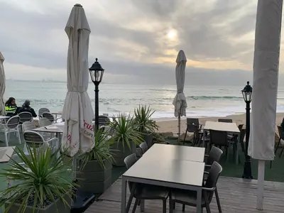 a patio with tables and umbrellas on the beach at Apartamento La Vasca in El Puerto de Santa María