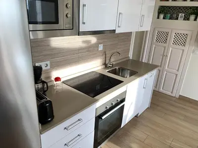 a kitchen with white cabinets and a sink and a microwave at Apartamento La Vasca in El Puerto de Santa María