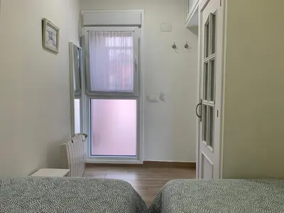 a bedroom with a window and a bed and a chair at Apartamento La Vasca in El Puerto de Santa María