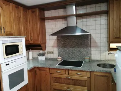 a kitchen with wooden cabinets and a stove top oven at ENTRE SAL Y ARENA in Cádiz