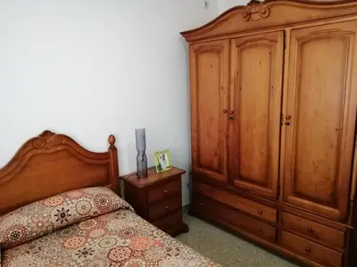 a bedroom with a bed and a wooden cabinet at ENTRE SAL Y ARENA in Cádiz