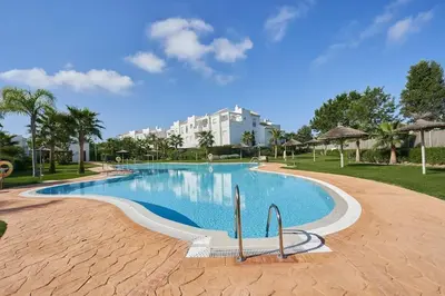 a swimming pool in a resort with a building in the background at Acogedora vivienda Costa Ballena in Chipiona