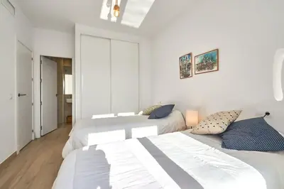 two beds in a bedroom with white walls at Acogedora vivienda Costa Ballena in Chipiona