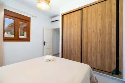 a bedroom with a large white bed and a wooden closet at VILLA SUR in Chiclana de la Frontera