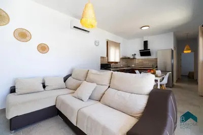 a living room with a white couch and a kitchen at VILLA SUR in Chiclana de la Frontera