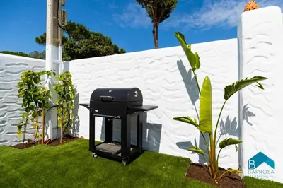 a barbecue grill in a yard next to a white fence at VILLA SUR in Chiclana de la Frontera