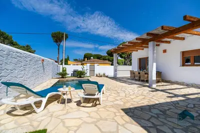 a patio with chairs and a table and a pool at VILLA SUR in Chiclana de la Frontera