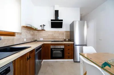 a kitchen with wooden cabinets and a stainless steel refrigerator at VILLA SUR in Chiclana de la Frontera
