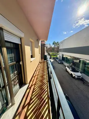 a balcony of a building with a car on the street at Piso céntrico y tranquilo con garaje incluido in Sanlúcar de Barrameda